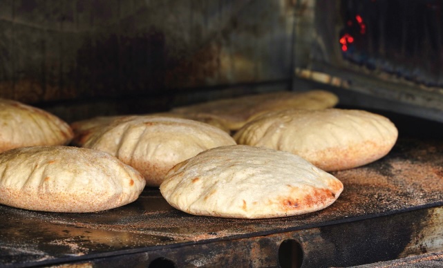 puffy pita bread being baked in an open oven